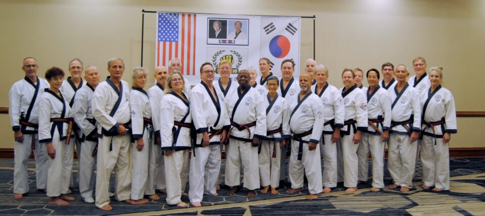A diverse group of martial artists in traditional uniforms, standing together in a conference room, celebrating a shared passion for martial arts.